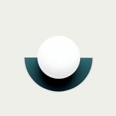 a white ball sitting on top of a black and green wall mounted light with an oval shape