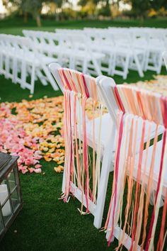 rows of white chairs with orange and pink striped sashes at an outdoor wedding ceremony