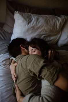 a man and woman laying in bed hugging each other