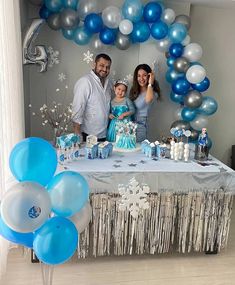 a man and woman standing next to a table with blue and white decorations on it