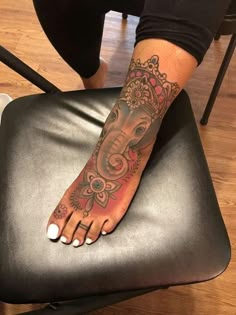 a person with a tattoo on their foot sitting in a chair and wearing a crown