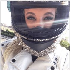 a woman wearing a motorcycle helmet with jewels on her face and neck is seen through the lens