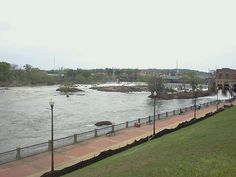 a view of a river from the top of a hill with people walking on it