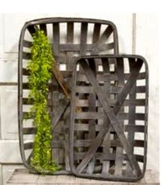 two metal baskets with plants in them on top of a wooden shelf next to a white wall