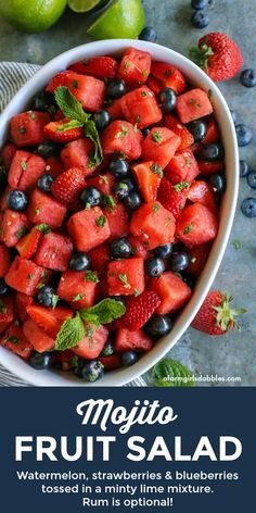 a bowl filled with watermelon, blueberries and limes next to two lime wedges