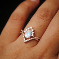 a woman's hand with a ring on it that has a rainbow stone in the middle