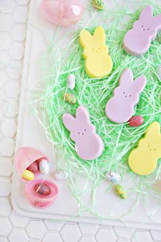 decorated cookies and candies in the grass with easter eggs around them on a white tray