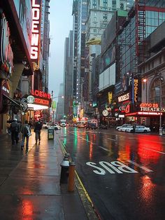 a city street filled with lots of tall buildings and neon signs on the side of it