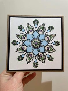 a hand holding up a card with an intricate design on it