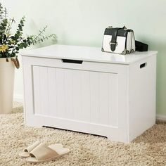 a white storage box sitting on top of a carpeted floor next to a potted plant