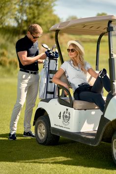 a woman sitting on top of a golf cart next to a man