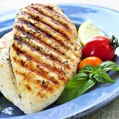 grilled chicken on a blue plate with tomatoes and basil