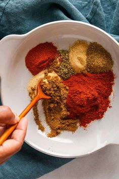 a person holding a spoon in a bowl filled with various spices and seasoning mix