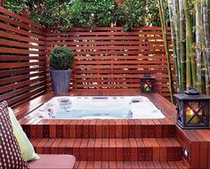 a hot tub sitting on top of a wooden deck next to a bamboo planter