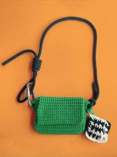 a small green purse with a black and white knitted tag hanging from it's side