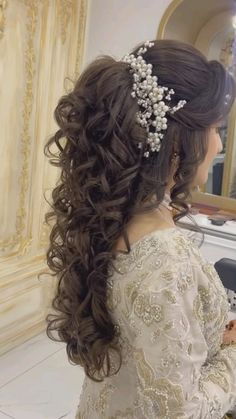 a woman is getting her hair done in a salon with long curls and flowers on her head