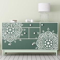 a green and white dresser in a room with a lamp on the side table next to it