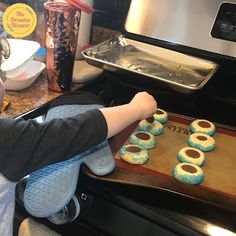 a child is sitting in front of an oven with doughnuts on the counter