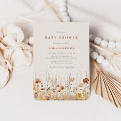 a baby shower is shown next to flowers and seashells on a white surface