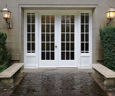 two stone benches sitting in front of a white door with glass panes on it