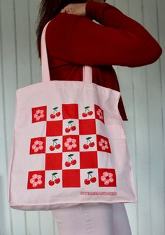 Pack up a picnic in this vibrant pink tote bag, displaying a checkerboard of cherries and cherry blossoms. It's the perfect accessory for spring! Totes are made of 12 oz cotton with self-fabric handles. They're very sturdy, you don't have to worry about overloading or ripping these. They measure a solid 10 inches wide by 13 1/2 inches high and expand to about 5 inches deep. Machine washable, tumble dry, iron as needed, bleach not recommended. Painted Canvas Bags, Picnic Tote, Pink Tote Bag, Painted Tote, Pink Tote Bags, Pack Up, Bag Ideas, Pink Tote, Cute Tote Bags