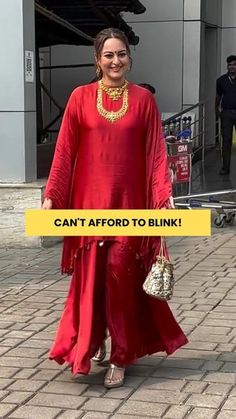 a woman in a red dress and gold necklace is walking down the street with her handbag