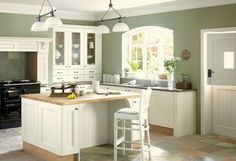 a large kitchen with white cabinets and an island in the middle is shown, along with two stools