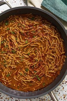 a pan filled with spaghetti and sauce on top of a table