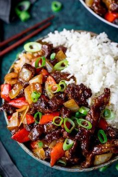 a bowl filled with rice, meat and vegetables next to chopsticks on a table