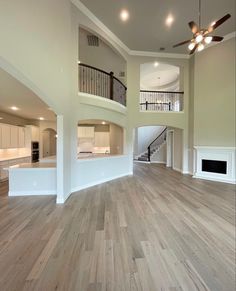 an empty living room with hard wood floors and white walls, two balconies on the second floor