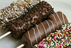 three chocolate covered donuts with sprinkles on them and one is dipped in chocolate