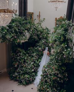 a bride standing in front of flowers and greenery