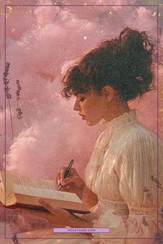 a woman sitting in front of a pink sky with clouds and writing on a book