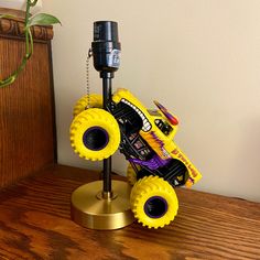 a yellow toy truck on top of a wooden table next to a plant and phone