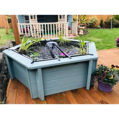 a garden box with plants growing in it on a wooden deck next to a house