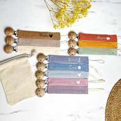 four personalized pouches with wooden buttons on them sitting next to some flowers and a straw hat