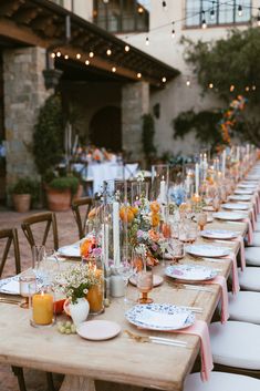 a long table set with plates and candles for an outdoor wedding reception at the hotel