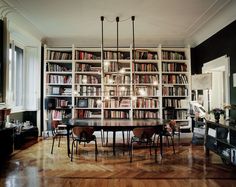 a dining room table surrounded by bookshelves and chairs