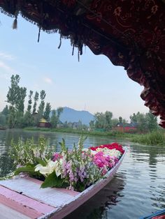 a boat filled with flowers on top of a river