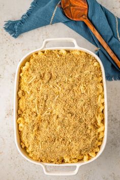 a casserole dish filled with macaroni and cheese next to a wooden spoon