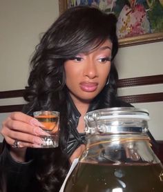 a woman holding a glass next to a tea pot