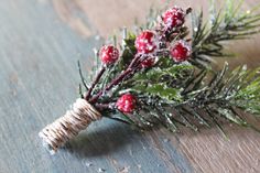 a pine branch with red berries and green leaves is on a wooden surface covered in snow