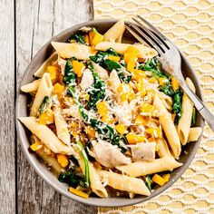 a pasta dish with spinach, chicken and parmesan cheese in a bowl