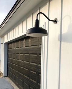 a garage door with a light on it next to a white wall and a black lamp