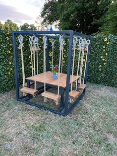 a wooden table sitting on top of a grass covered field next to a tall fence