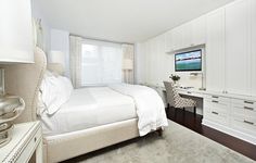 a bedroom with white furniture and a flat screen tv