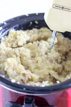 the food in the slow cooker is being mixed with other ingredients to make mashed potatoes