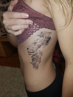 a woman with a lion tattoo on her stomach is looking down at the side of her body