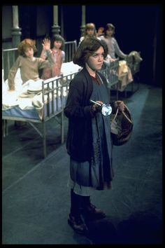 a woman standing in front of a hospital bed holding an object with her hand and looking at the camera