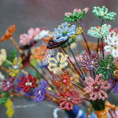 there are many colorful flowers in the vase on the table and one is made out of beads